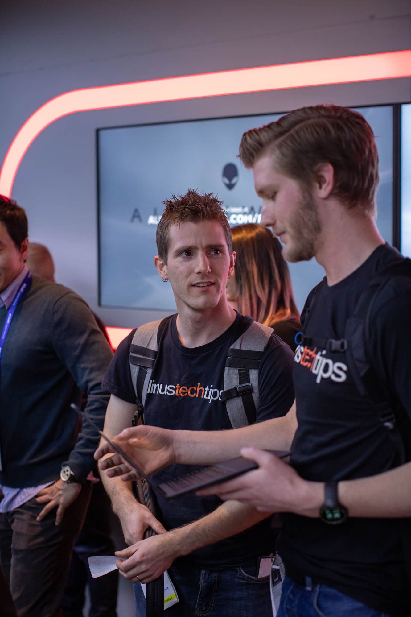 Visitor at a product demo table, screens in the background