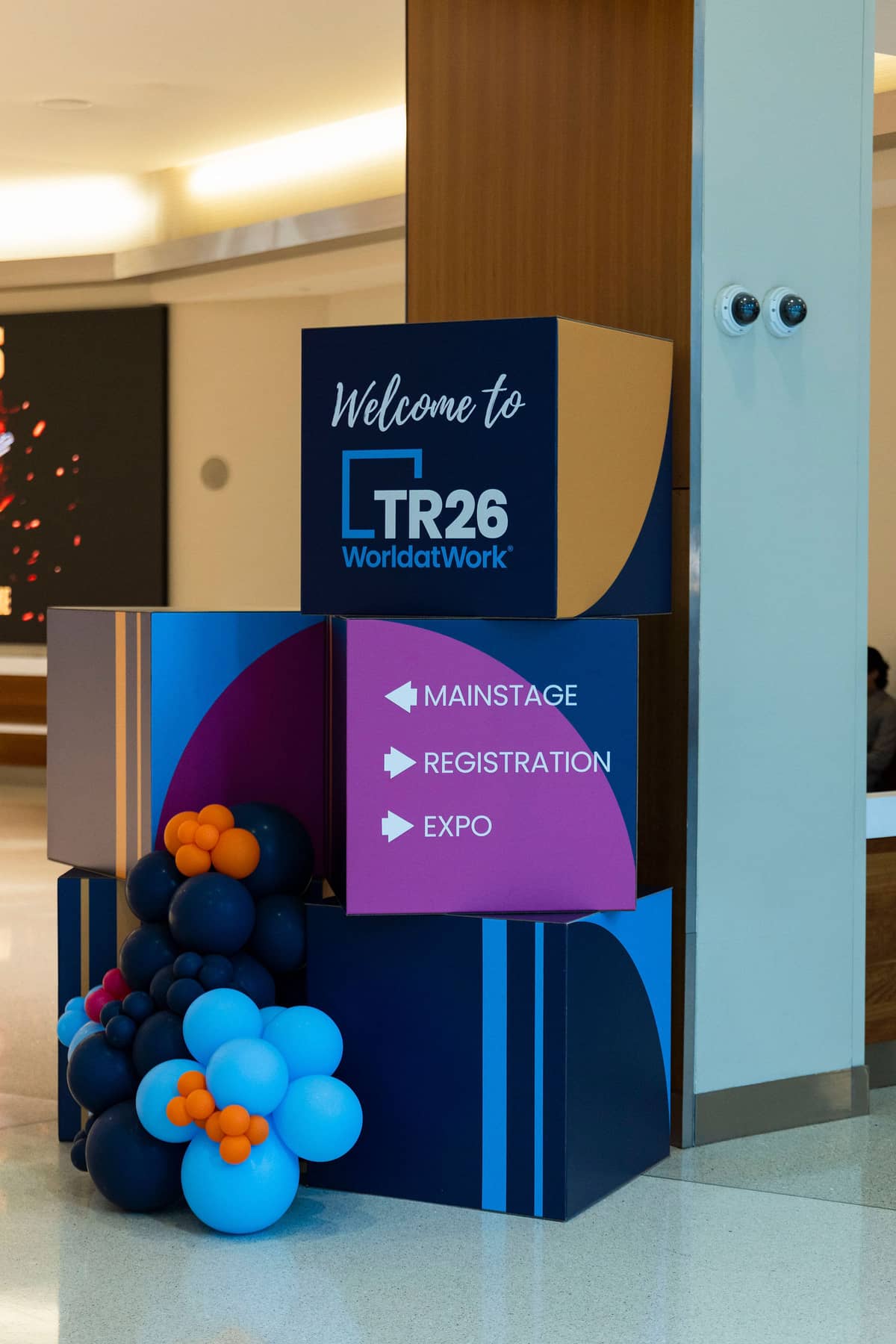 Branded wayfinding cubes and balloons at World at Work Total Rewards 2026 in Austin, pointing to mainstage, registration, and expo